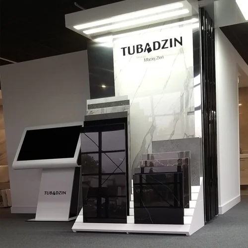 Ekspozycja płytek ceramicznych Tubądzin Maciej Zień w salonie, z różnymi wzorami i kolorami, oraz interaktywny kiosk.